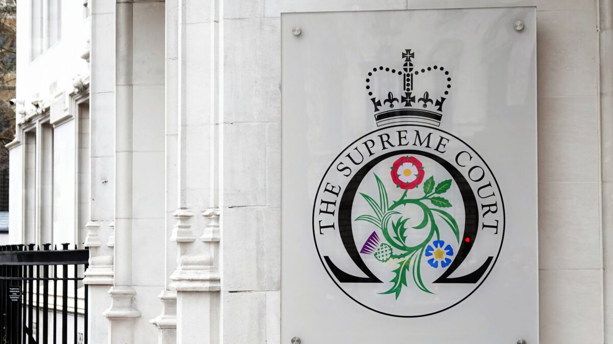 The entrance to the Supreme Court with a sign displaying the official Supreme Court badge in Westminster, London, UK.