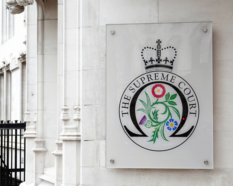 The entrance to the Supreme Court with a sign displaying the official Supreme Court badge in Westminster, London, UK.