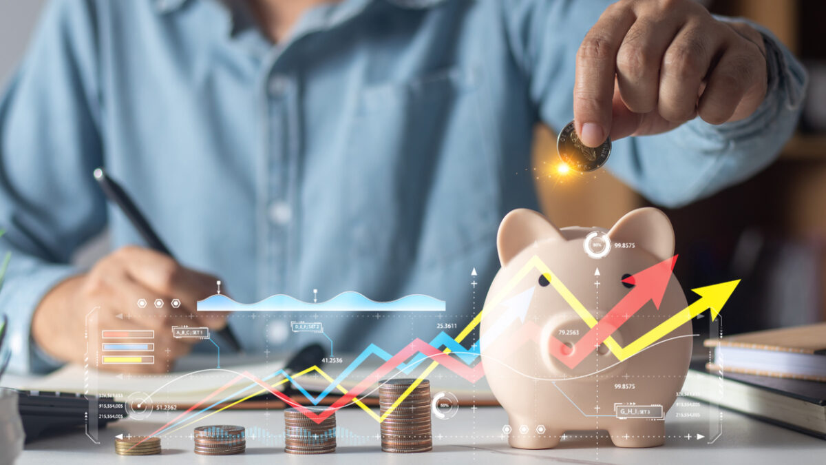 Man putting coins in piggy bank and taking notes in notebook money saving concept business