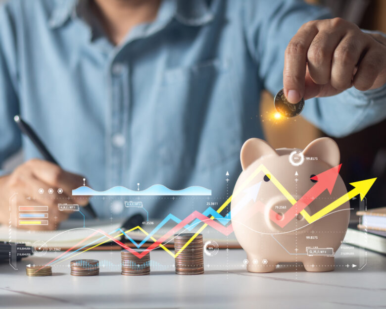 Man putting coins in piggy bank and taking notes in notebook money saving concept business