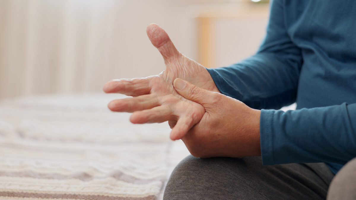 Senior man, hands and arthritis with joint pain, inflammation or Parkinson disease on bed at home. Closeup of elderly male person with fibromyalgia, injury or sore ache of muscle strain in bedroom