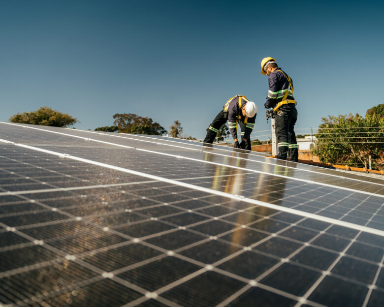 Two workers installing solar panel on roof