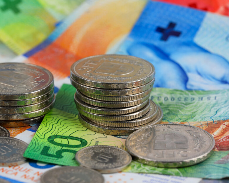 The Swiss currency, CHF, is visible. Coins are shown lying on paper money. It can be used to illustrate a wide range of financial topics.