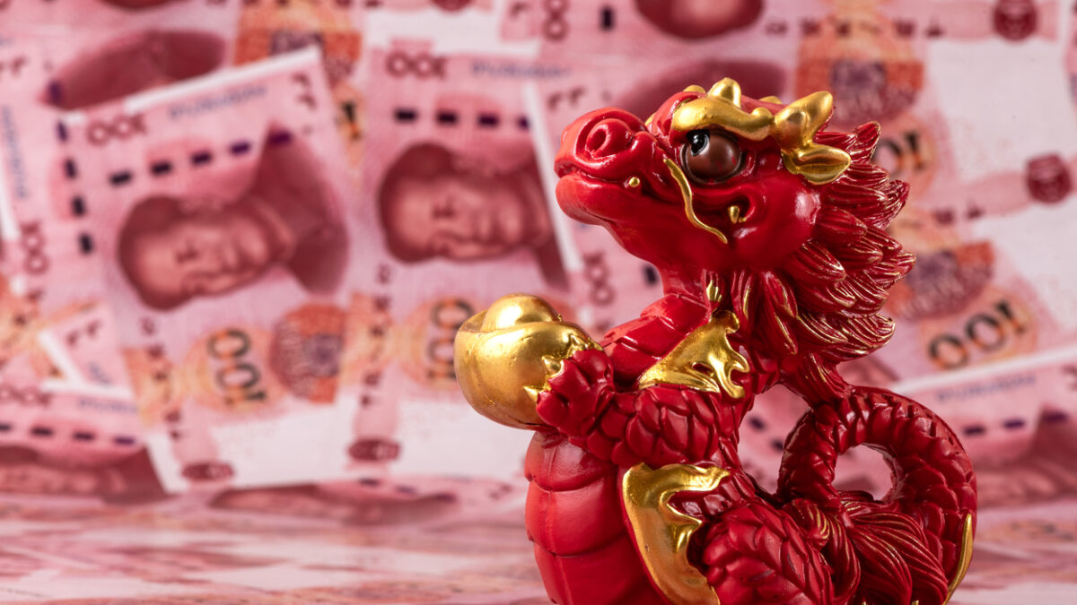 A figurine of a symbolic Chinese dragon - a symbol of wisdom, strength, longevity and power, bringing good luck and prosperity against the background of 100 Chinese yuan bills.