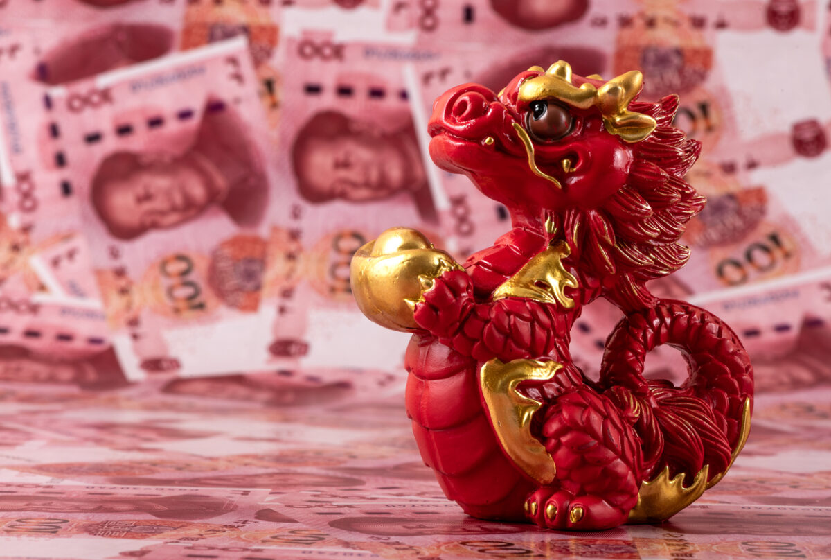 A figurine of a symbolic Chinese dragon - a symbol of wisdom, strength, longevity and power, bringing good luck and prosperity against the background of 100 Chinese yuan bills.