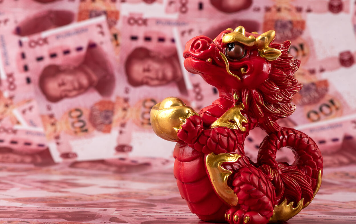 A figurine of a symbolic Chinese dragon - a symbol of wisdom, strength, longevity and power, bringing good luck and prosperity against the background of 100 Chinese yuan bills.