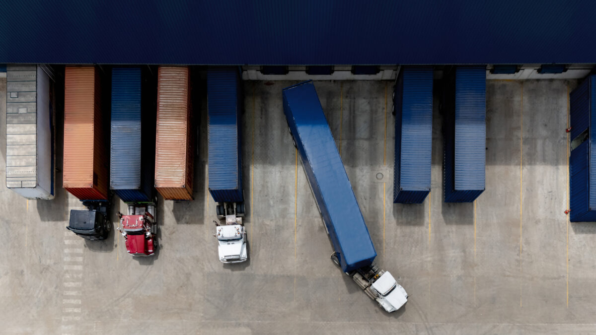 Description Aerial view of a truck leaving the loading dock at a distribution warehouse - freight transportation concepts
