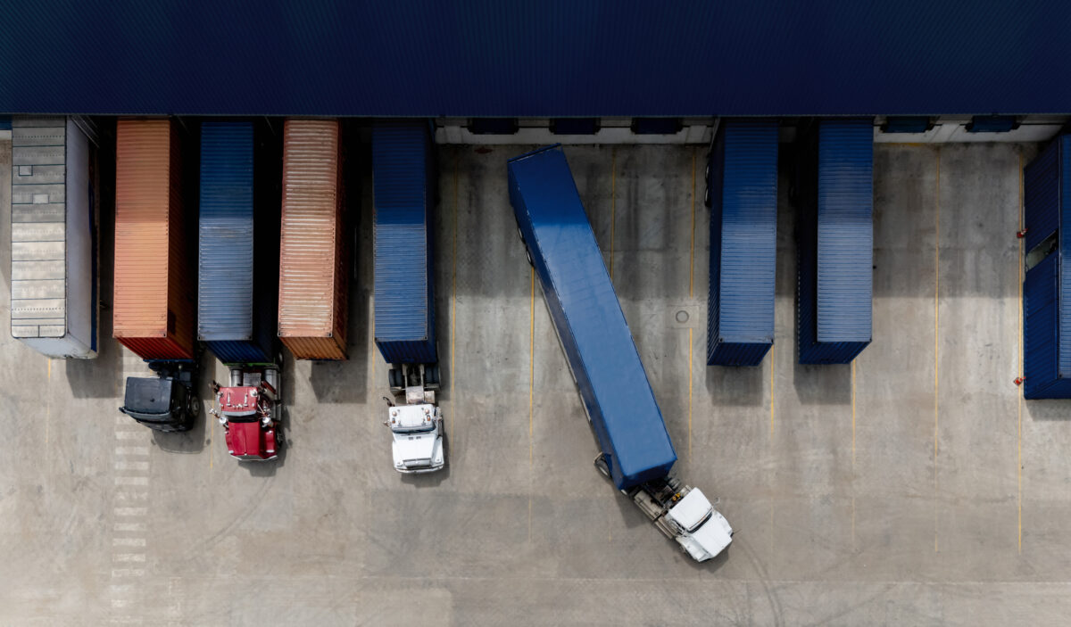 Description Aerial view of a truck leaving the loading dock at a distribution warehouse - freight transportation concepts