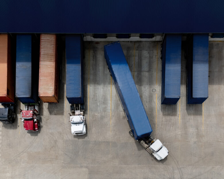 Description Aerial view of a truck leaving the loading dock at a distribution warehouse - freight transportation concepts