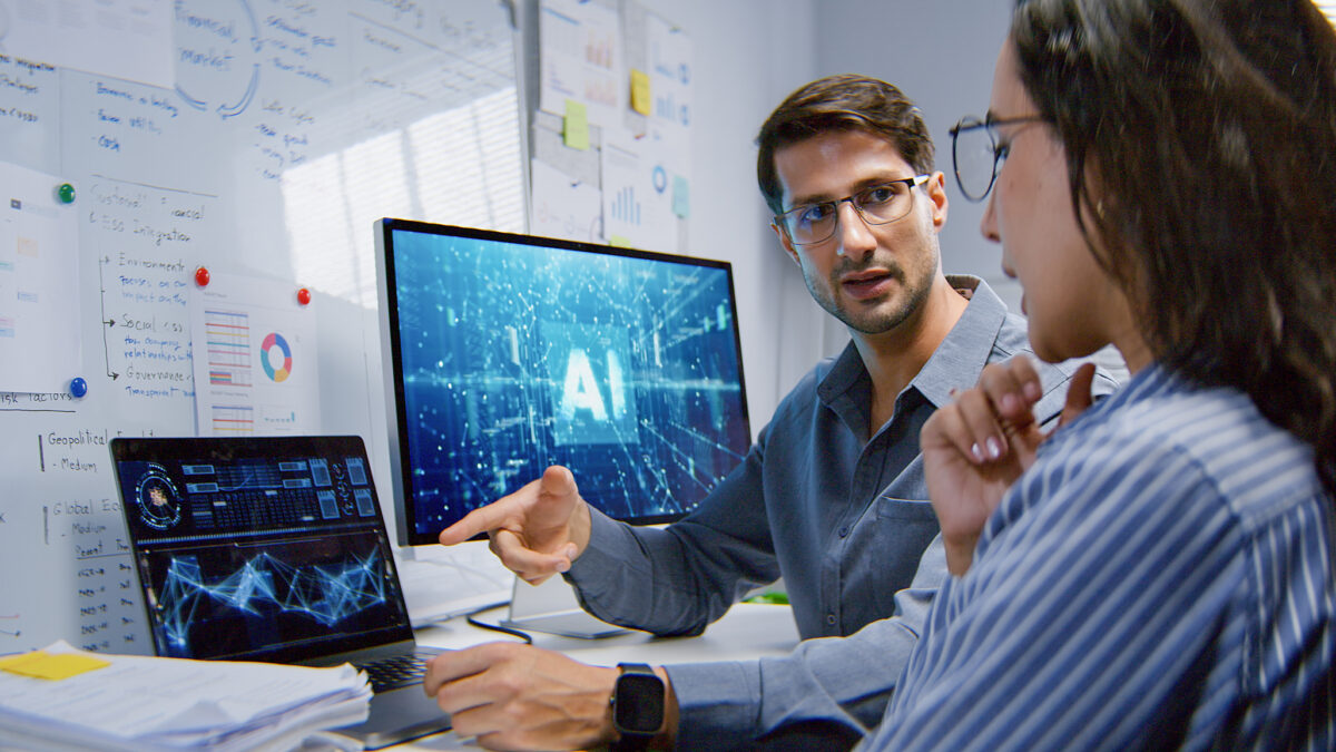 White Latin male and female programmer engineer use AI software on laptop computer, meeting discussion at home office at night. Internet information technology, artificial intelligence at work concept