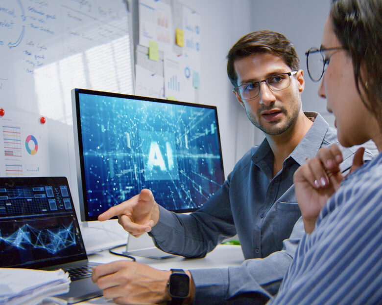 White Latin male and female programmer engineer use AI software on laptop computer, meeting discussion at home office at night. Internet information technology, artificial intelligence at work concept
