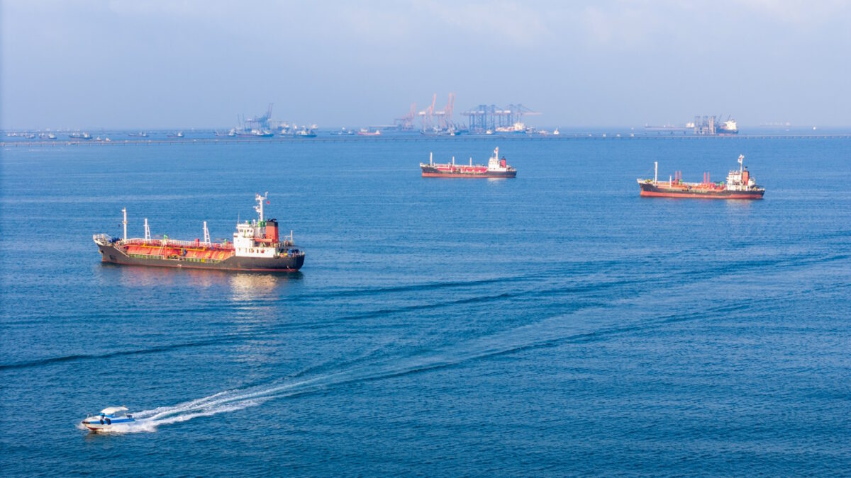 LPG gas and oil tanker ships anchored in the ocean, with a fast patrol boat in the foreground. Global energy transport, war energy crisis, and Strait of Hormuz blockade concept.