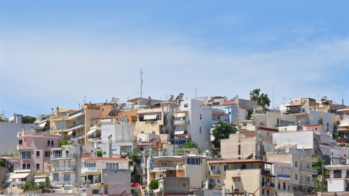 Many local buildings are seen along the street up hill in Athens, Greece.