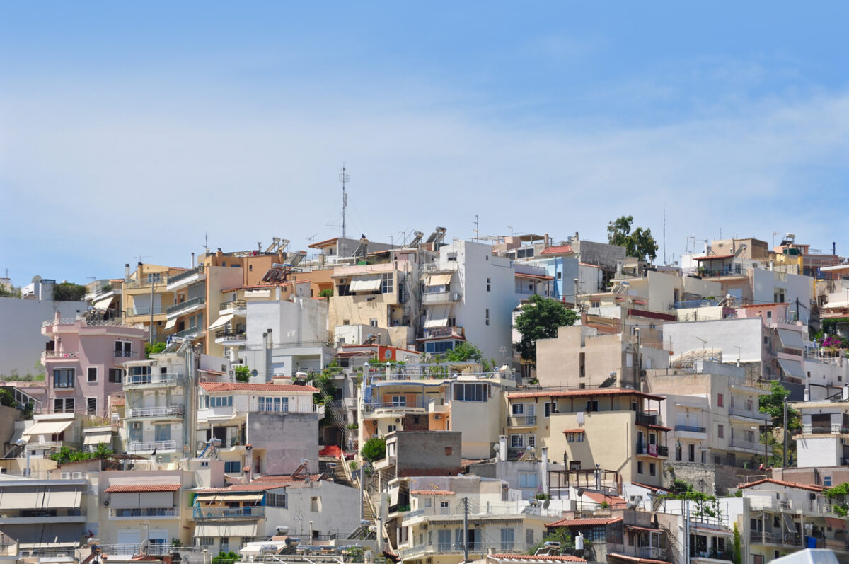 Many local buildings are seen along the street up hill in Athens, Greece.