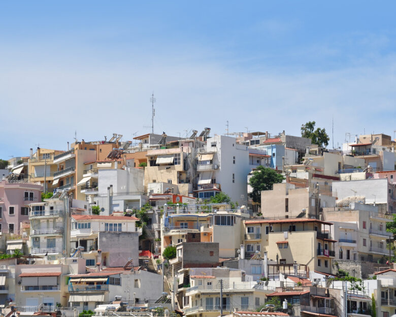Many local buildings are seen along the street up hill in Athens, Greece.