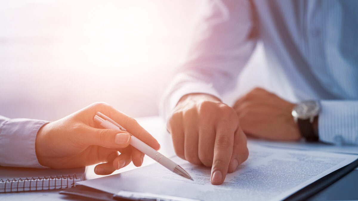 Business people negotiating a contract. Human hands working with documents at desk and signing contract.