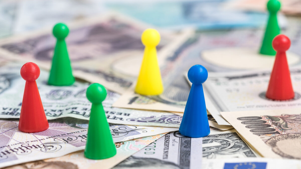 World money game by colorful plastic game figurines on international major countries banknotes, US dollar, Japanese yen, Euro, Chinese yuan.