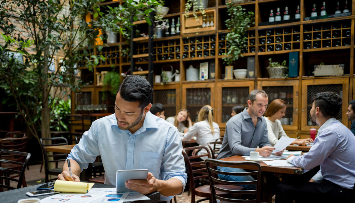 Business owner working at a cafe doing the books using a digital tablet - small business concepts