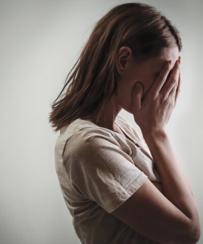 Portrait of depressed woman, covering face with her hands, side view