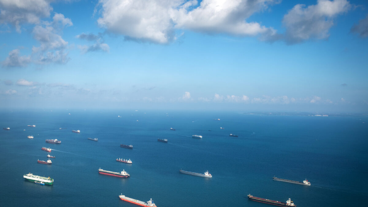 Transportation and Container ships wait on the ocean in front of the port of Singapore.