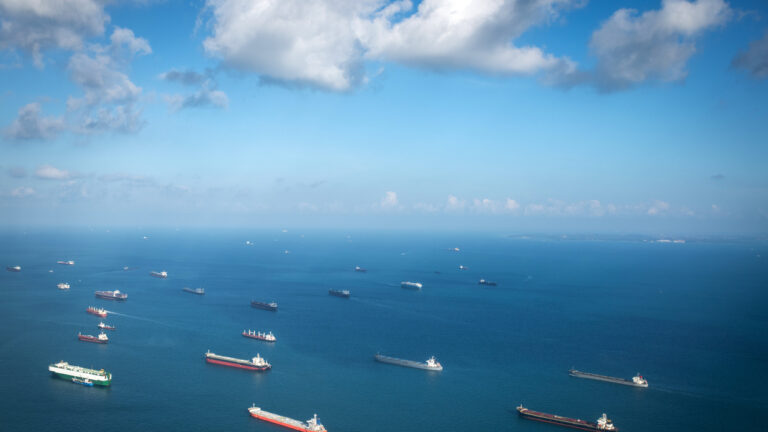 Transportation and Container ships wait on the ocean in front of the port of Singapore.