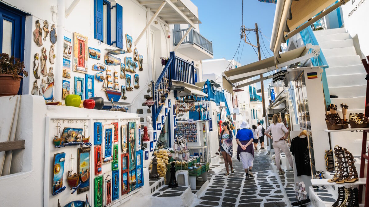 Mykonos, Greece-May 8, 2018-Shoppers explore the narrow alleys of Mykonos Town where colorful merchandise is displayed in hopes of catching a tourists eye.