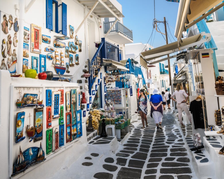 Mykonos, Greece-May 8, 2018-Shoppers explore the narrow alleys of Mykonos Town where colorful merchandise is displayed in hopes of catching a tourists eye.