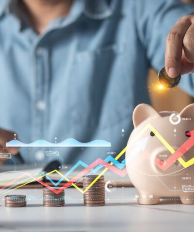 Man putting coins in piggy bank and taking notes in notebook money saving concept business