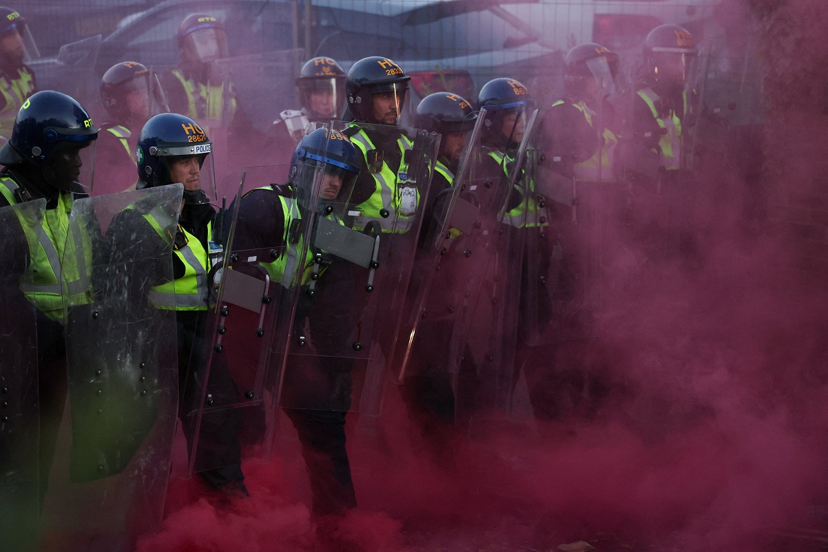 Police officers stand guard amid colored smoke during a demonstration following the conviction of Vikrum Digwa for the murder of student Henry Nowak, in Southampton, Britain, June 2, 2026. REUTERS