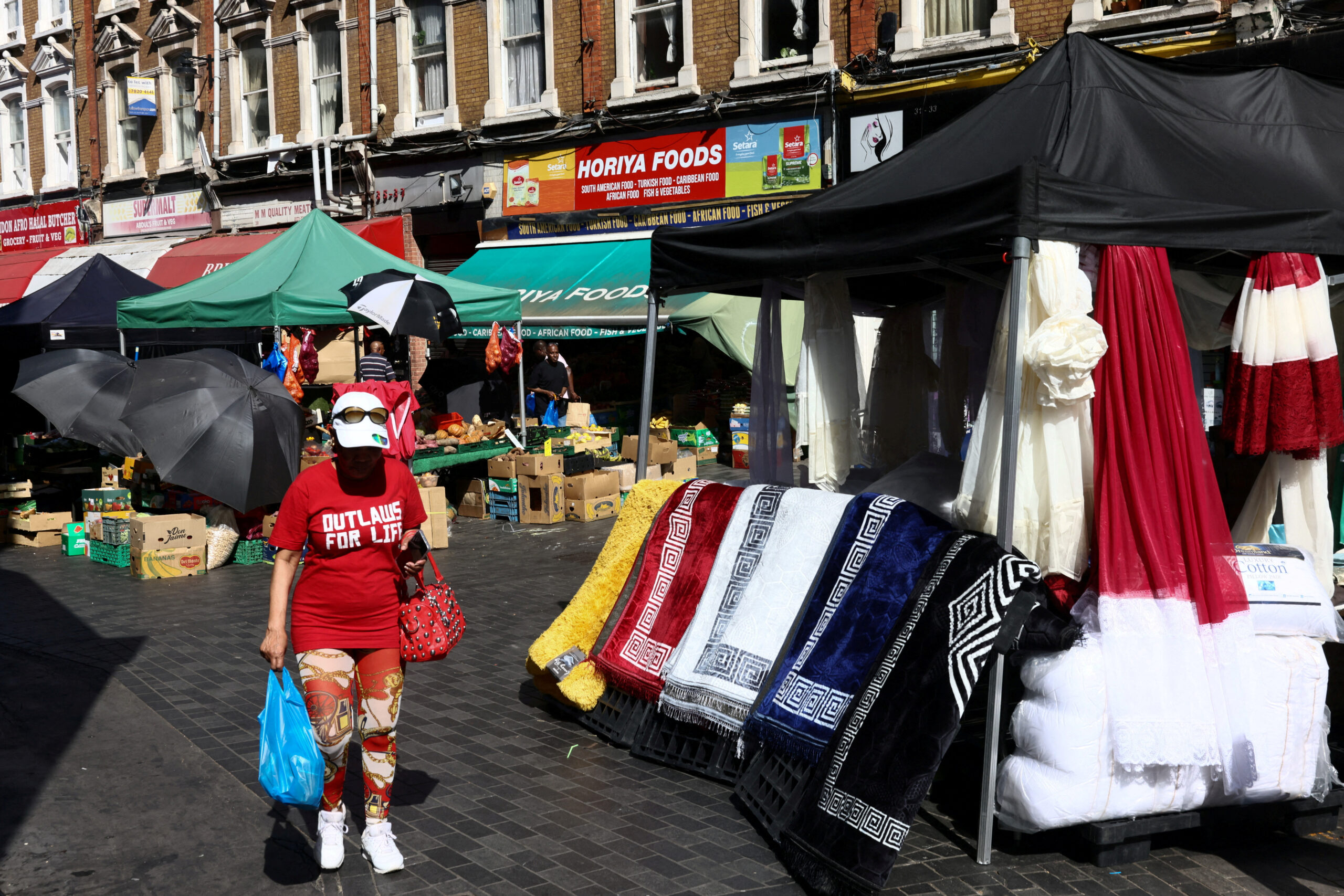 FILE PHOTO: A woman carries her shopping through Brixton market, as the record for the hottest ever May temperature in the UK has been broken for the second day in a row, in London, Britain, May 26, 2026. REUTERS/Jack Taylor/File Photo
