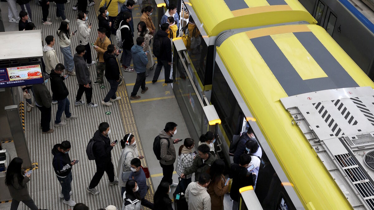 FILE PHOTO: Commuters line up to board a train at a subway station near the Zhongguancun tech hub, during morning rush hour in Beijing, China March 27, 2025.