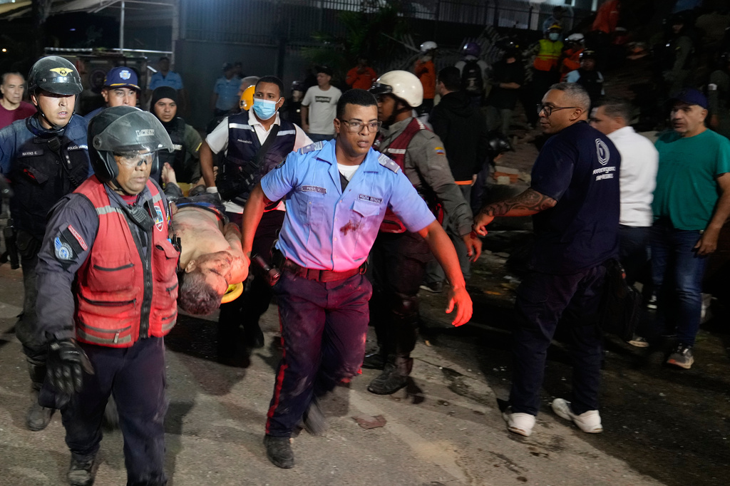 Διασώστες μεταφέρουν άνδρα που σώθηκε από τα συντρίμμια κτιρίου