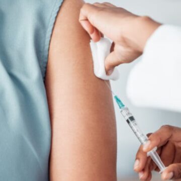 Hands, medical and doctor with patient for vaccine in a clinic for healthcare treatment for prevention. Closeup of a nurse doing a vaccination injection with a needle syringe in a medicare hospital.
