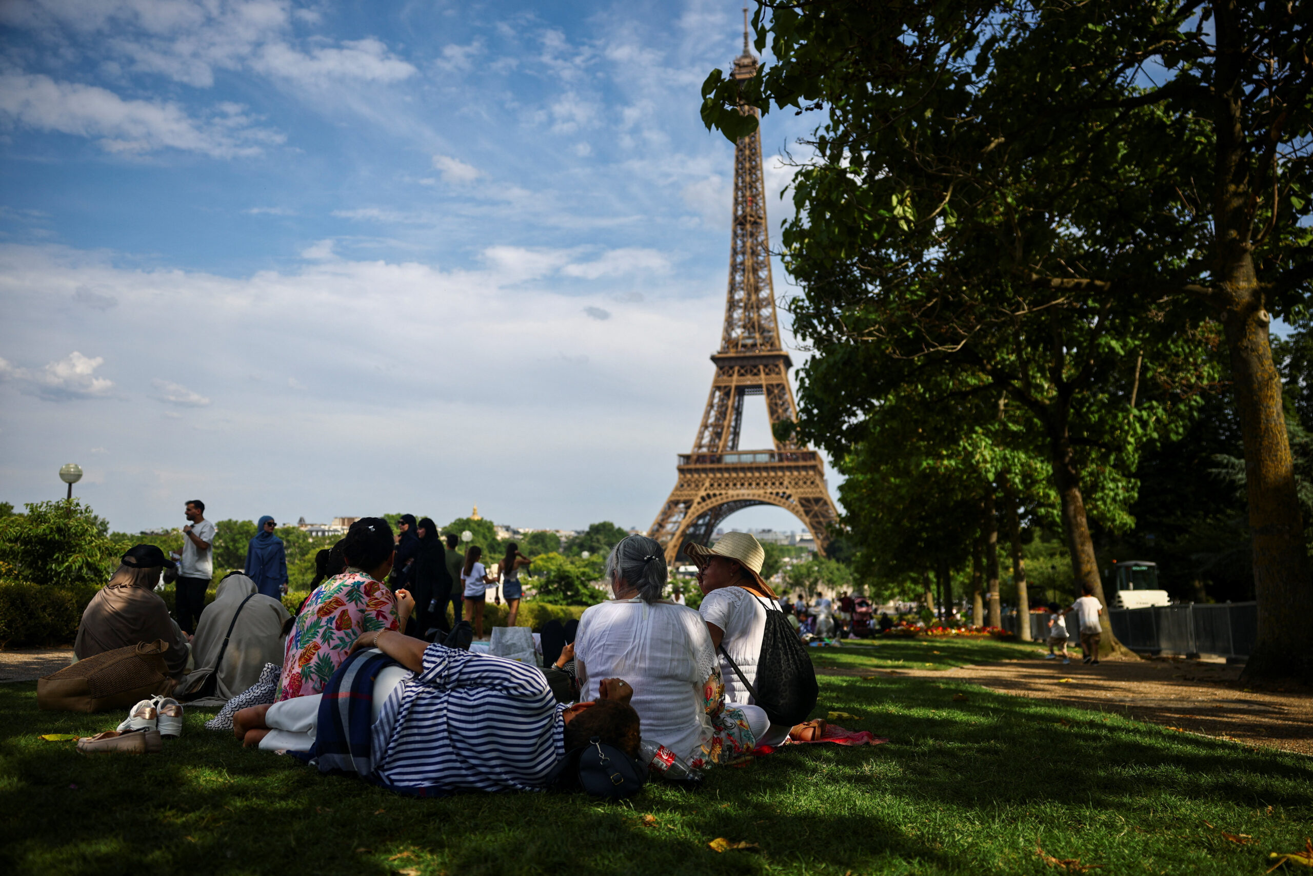 People rest in the shade of trees near the Eiffel Tower as temperatures rise in Paris during a second heatwave affecting a large part of France, June 20, 2026. REUTERS/Sarah Meyssonnier