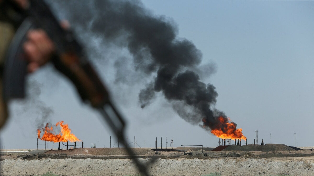 Gas flares burn at the Rumaila oil field as an Iraqi Energy Police officer secures the area in Basra, Iraq, June 8, 2026.