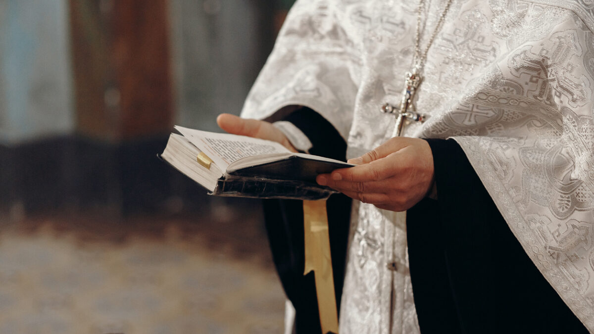 Priest reading holy bible in christian church during orthodox wedding ceremony, spiritual ritual concept