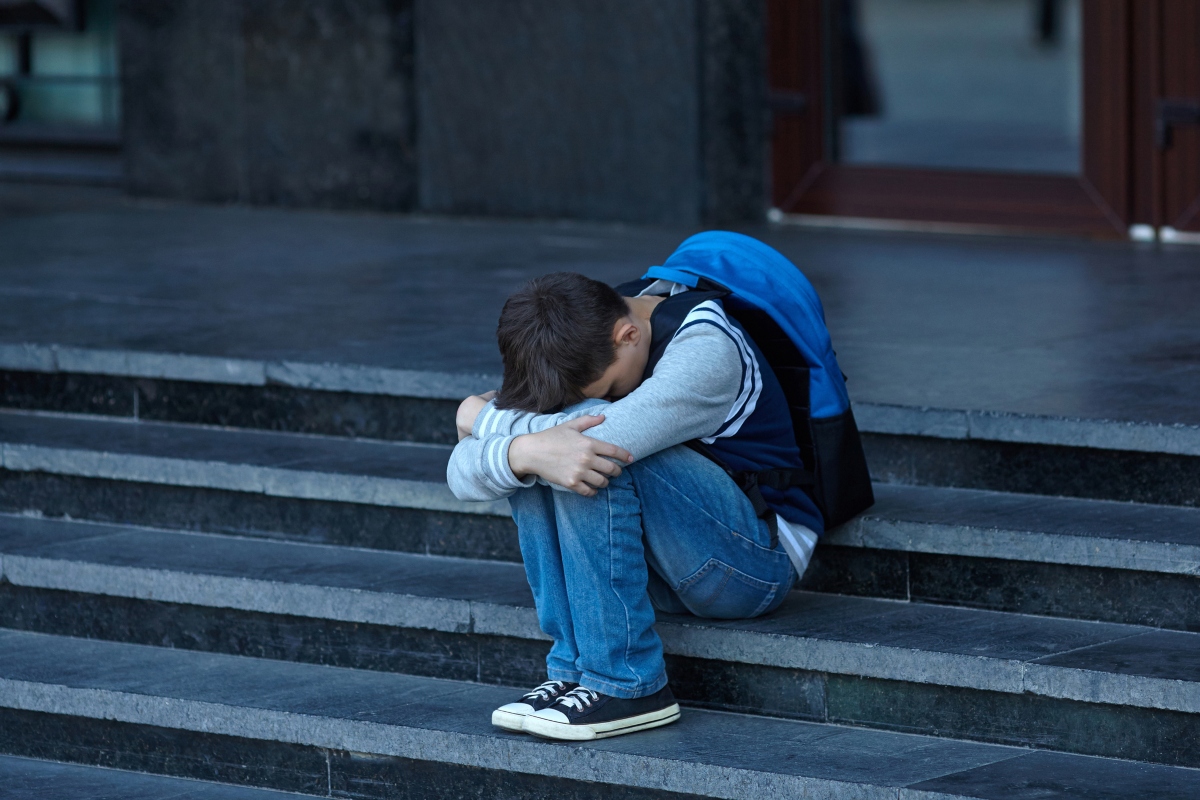 Schoolboy crying in the yard of the school. Negative emotion.