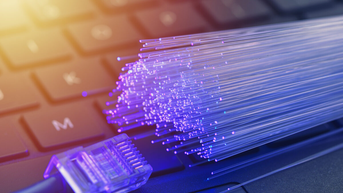 Fiber optics in blue, close up with ethernet and keyboard background, warm lens flare