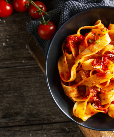 Tasty appetizing pasta tagliatelle spaghetti with tomato sauce and parmesan. Served on plate on wooden table. Closeup. Horizontal with copy space.