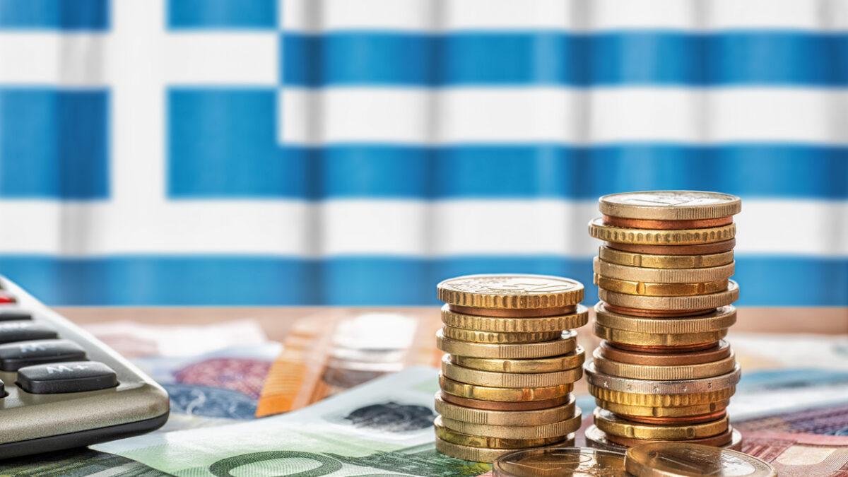 Euro banknotes and coins in front of the national flag of Greece