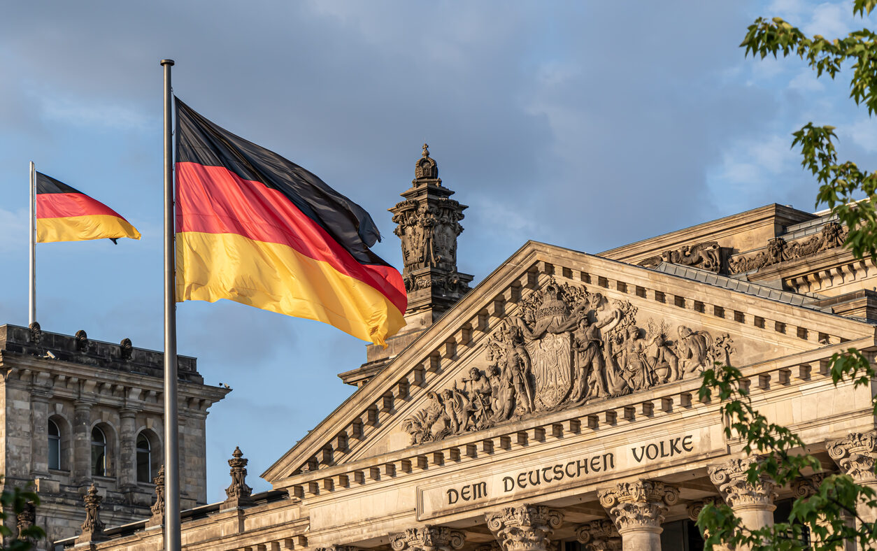 Federal Republic of Germany, German national flag at the Parliament building waving on the blue sky background, DE