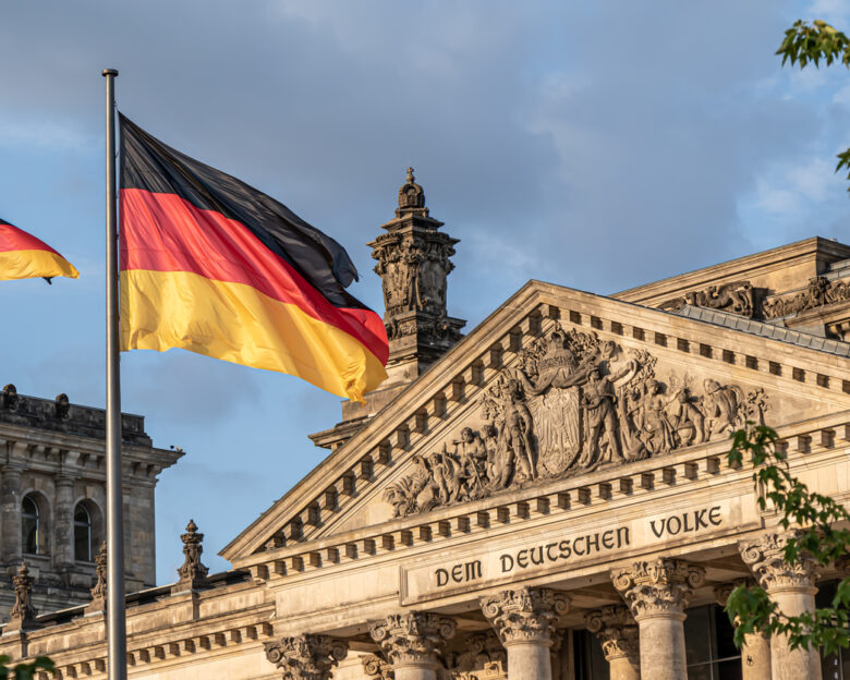 Federal Republic of Germany, German national flag at the Parliament building waving on the blue sky background, DE