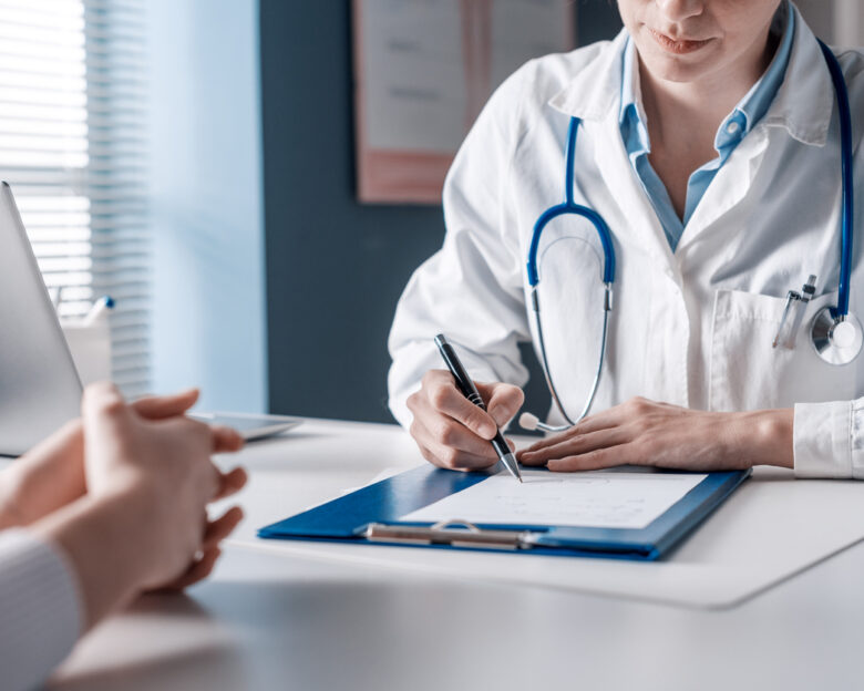 Doctor sitting at desk and writing a prescription for her patient