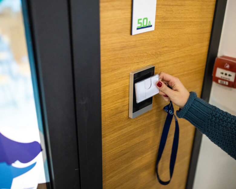 Unrecognizable Caucasian female staff using ID enter key to open the door at the building