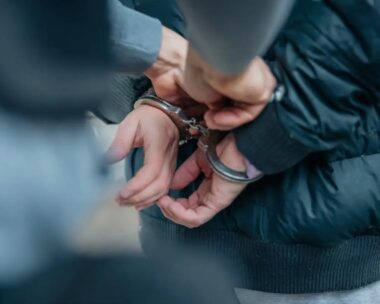 Policeman unlocking a handcuffs on the criminal's back.
