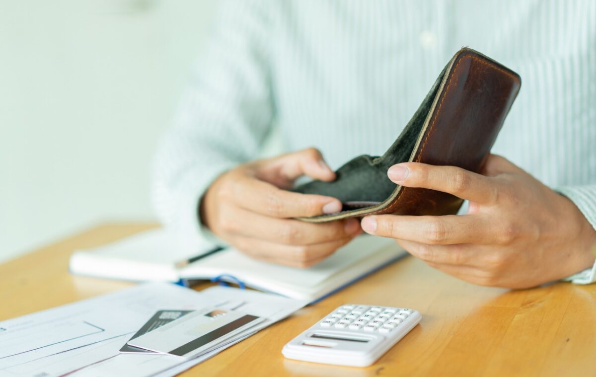 close up man hand opening empty wallet over calculator , debt expense bills monthly and credit card at the table in home office , managing payroll,money risk financial concept