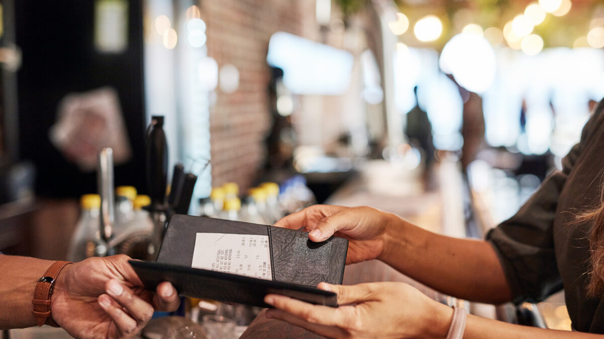 Hands with bill, food service and people in restaurant, customer with receipt and payment with cashier or waiter. Fine dining, dinner and check at cafe, catering and hospitality with finance