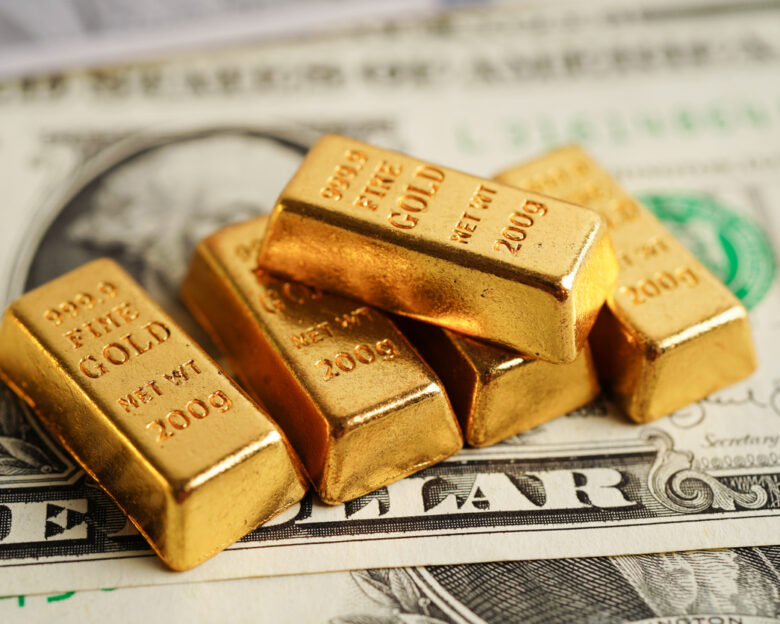 Gold bars on US dollar banknote money, finance trading investment business currency concept.