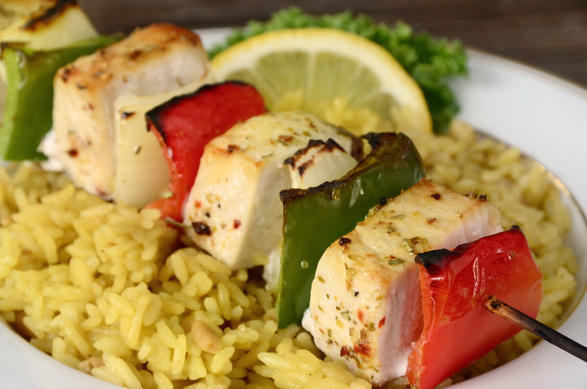 "A grilled shish kebab made of fresh swordfish, bell peppers and onions served over rice pilaf."