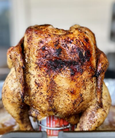 A beer can chicken, seasoned with spices and flavored by the beer inside of the can, is perched on a beer can chicken stand shortly after coming off a backyard barbecue grill.